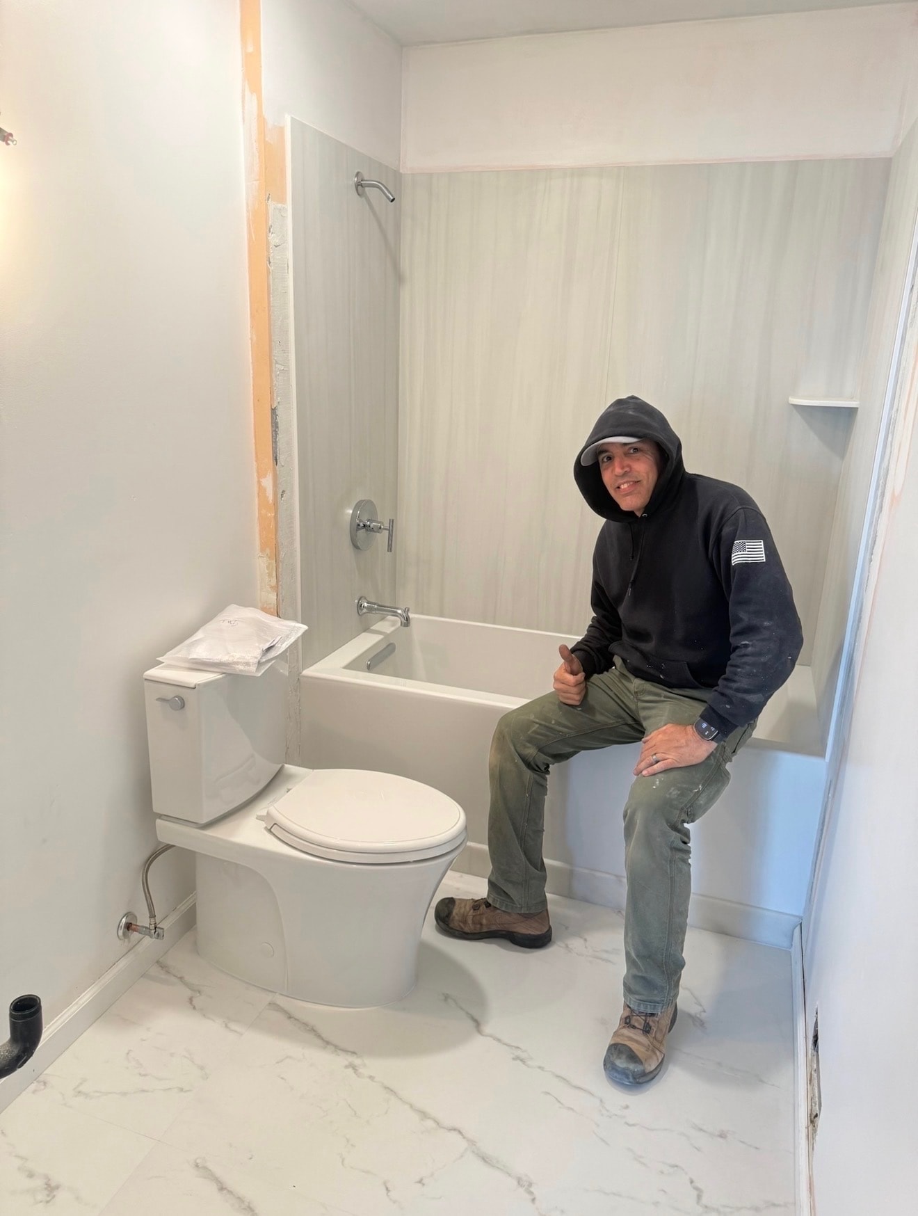 David sitting on the edge of a newly installed tub in a finished bathroom